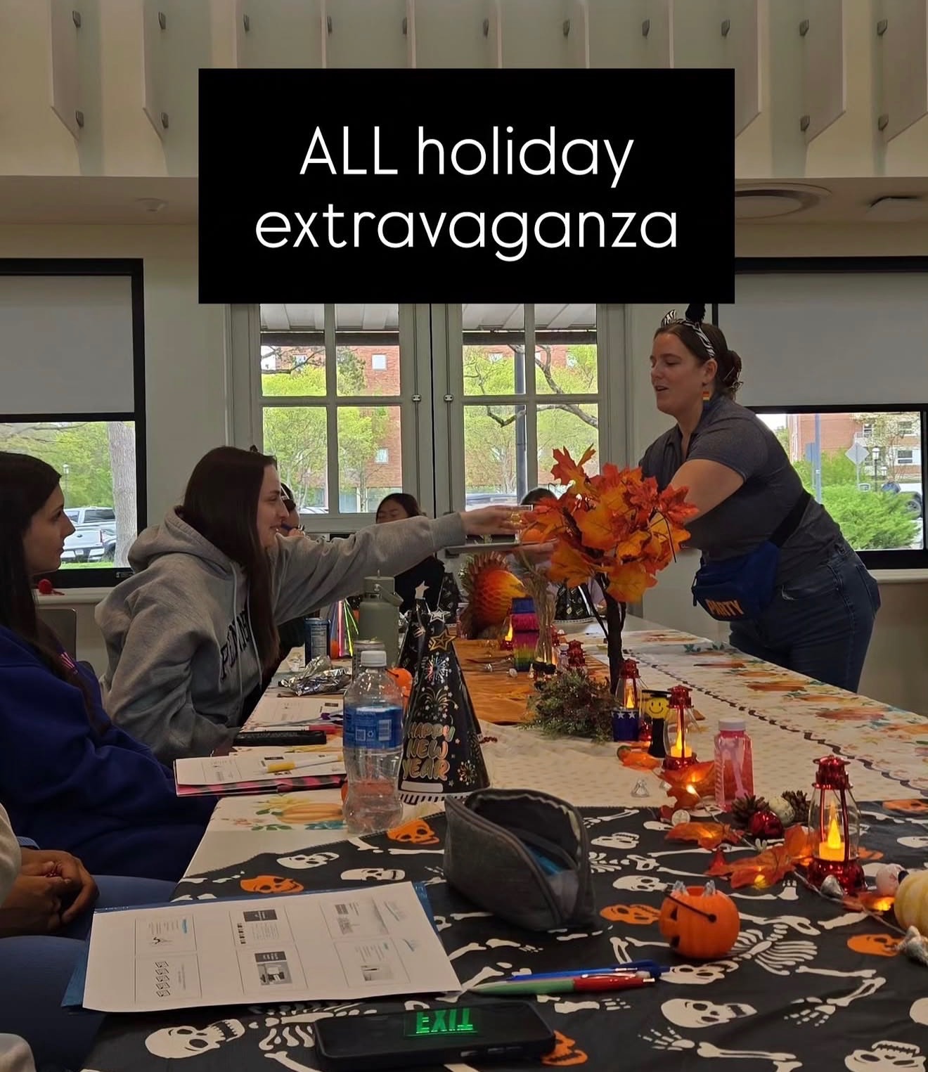 Sydney Pons sharing sparkling cider with students around a classroom table decorated for several holidays.